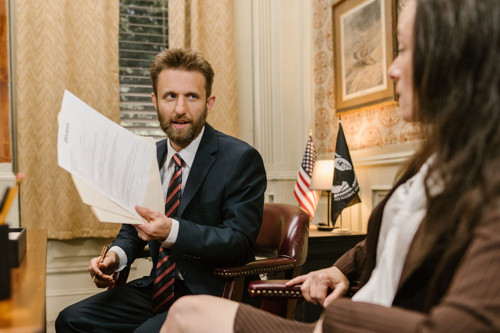 Illustrative stock photograph of two adults discussing documents in an office consultation.