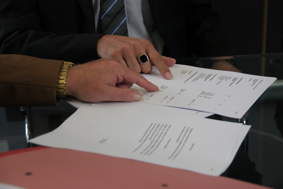 Hands reviewing the terms of a printed document; illustrative stock photograph.